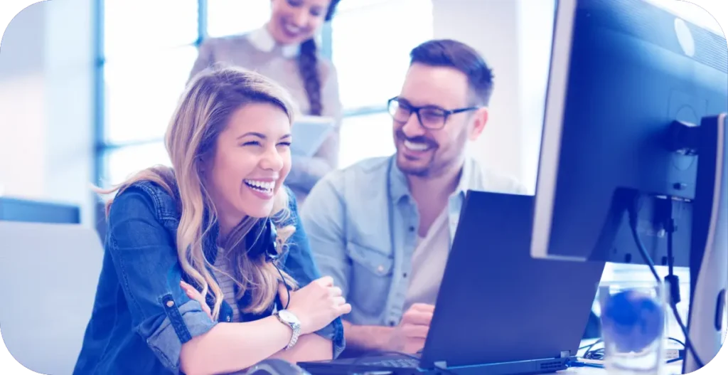 People looking at a laptop screen smiling