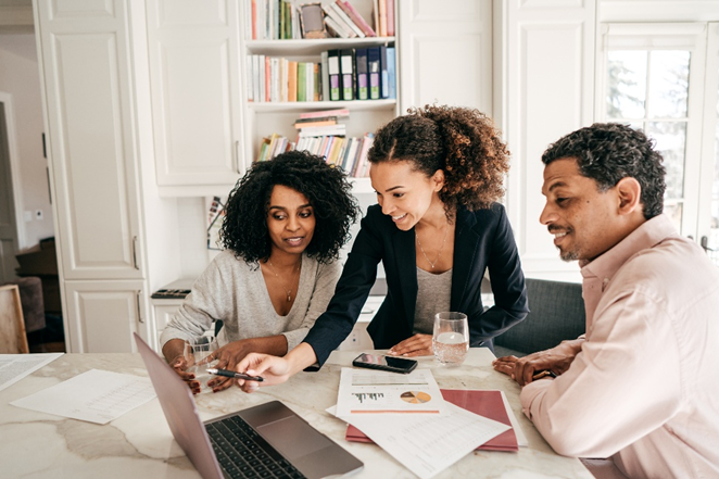 Image of 3 people, 2 people trying to learn from the other person who is teaching, reviewing the reports